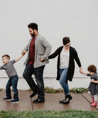 a family of four, holding hands and walking around happily