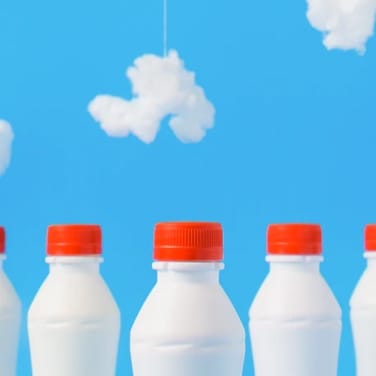 a group of milkbottles on a blue background with clouds made of cotton