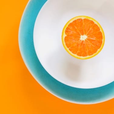 an orange on white and green plates on orange background