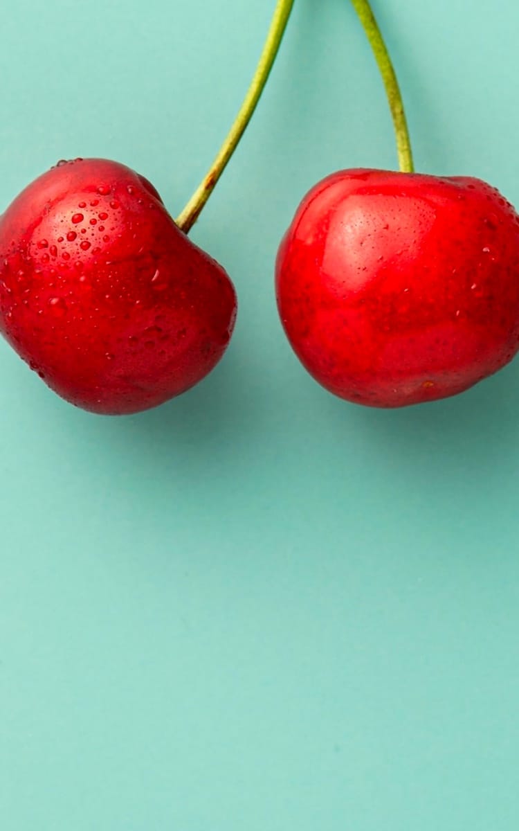 a couple of cherries on a light green background