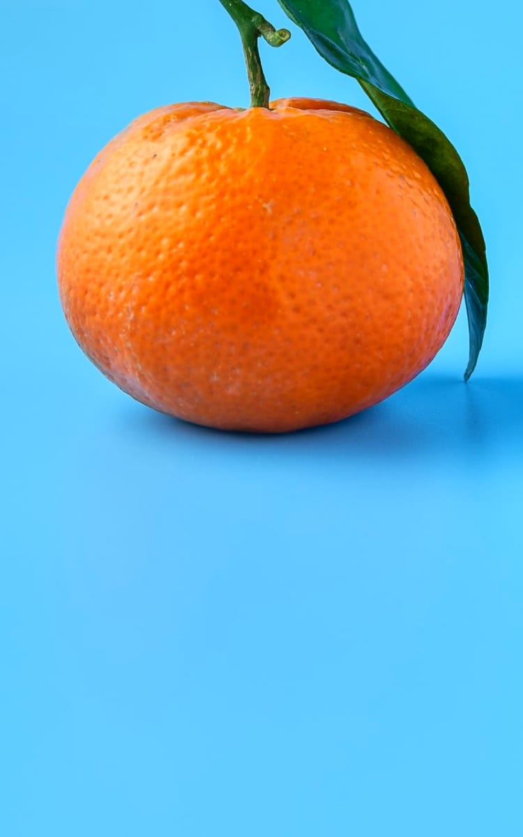 a tangerine on a light blue background